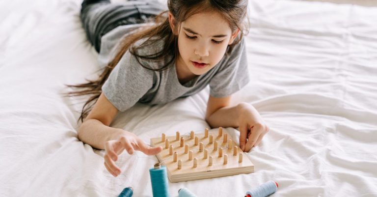 Cuando se cancela tu viaje y tu hijo pequeño se porta mal 6 Girl plays with a geoboard and threads, fostering creativity and mindful learning.